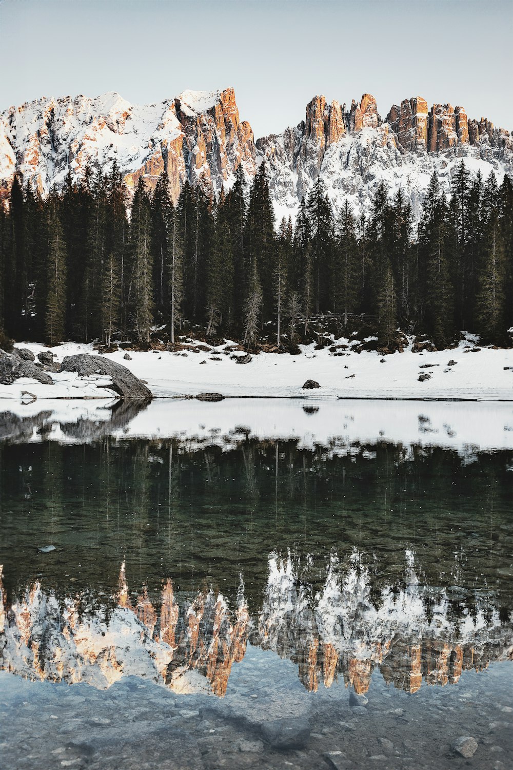 Un lago rodeado de montañas cubiertas de nieve y pinos