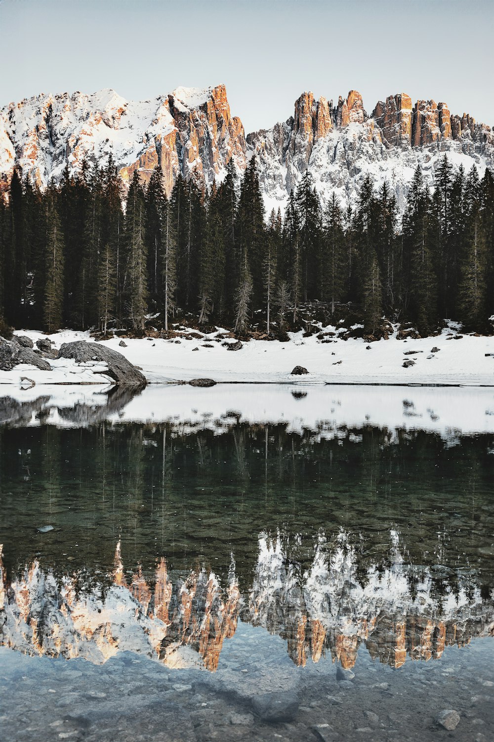 a lake surrounded by snow covered mountains and pine trees