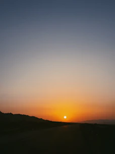 Sunset view over a flat, open land plot with distant mountains and a small creek running through.