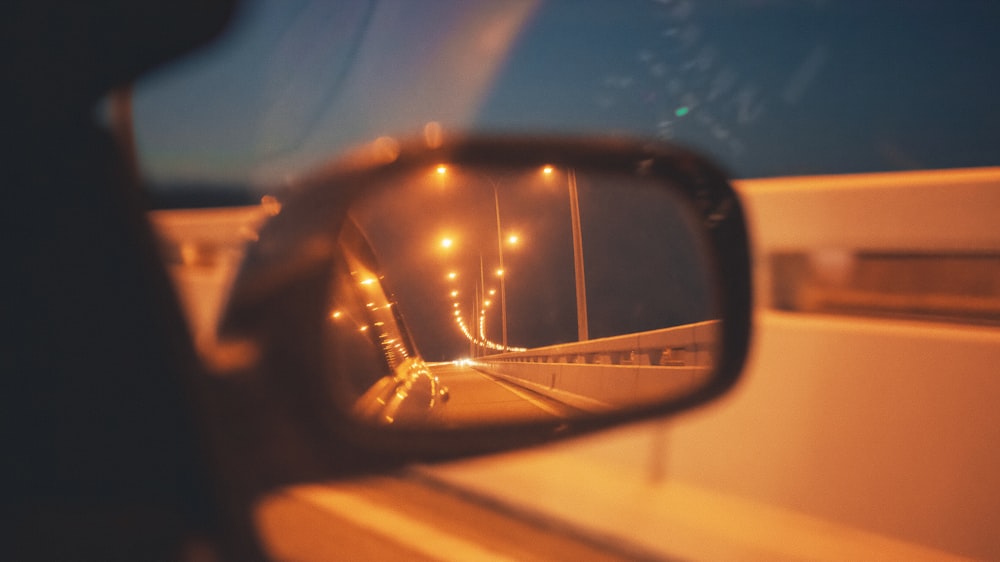 a rear view mirror reflecting a bridge at night