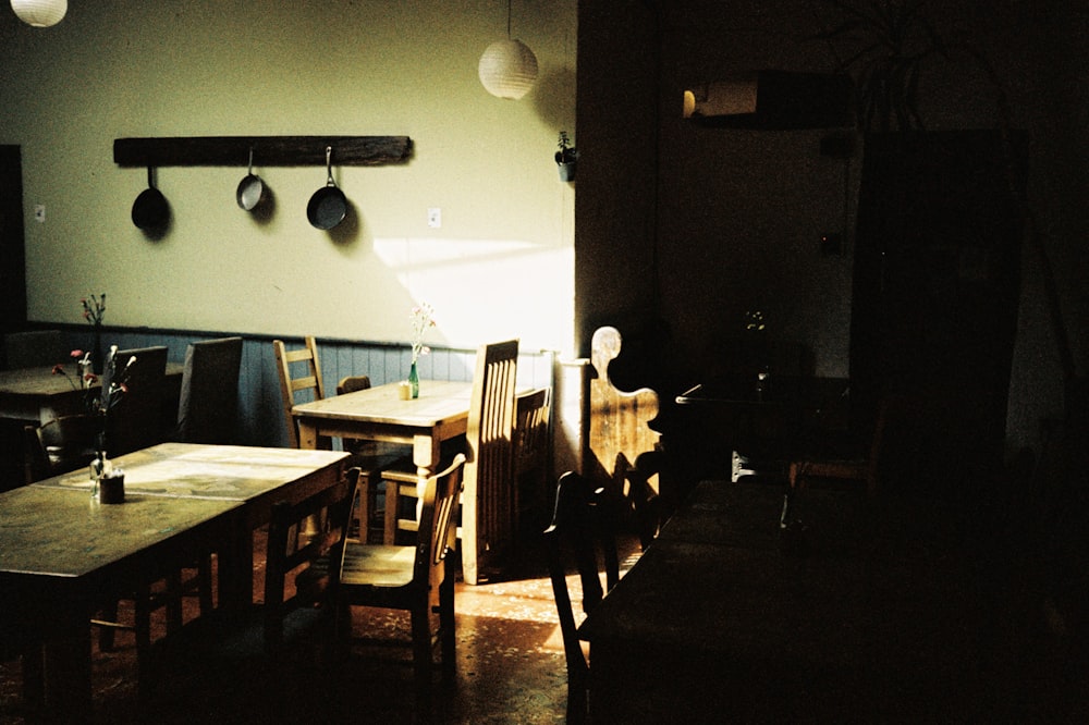 a dimly lit room with several wooden tables and chairs