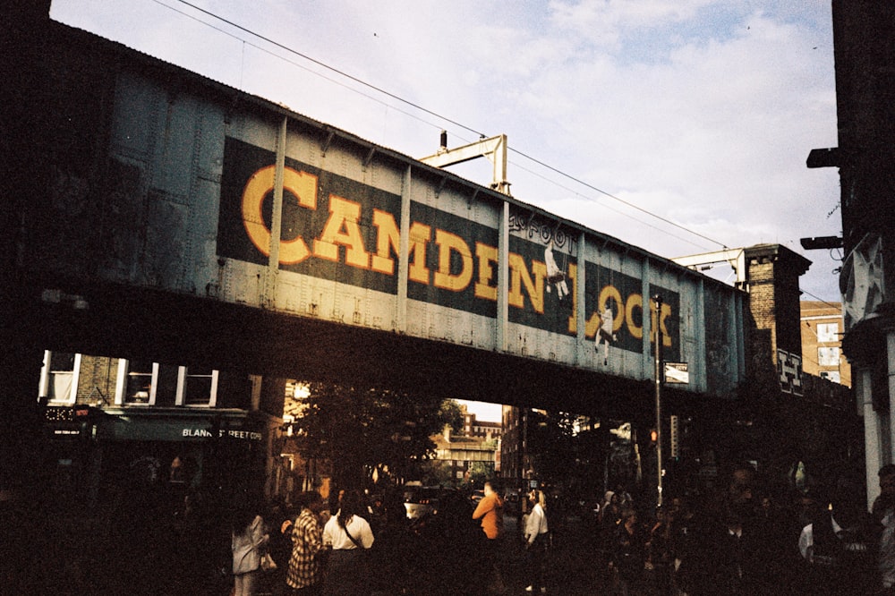 a group of people standing under a train bridge