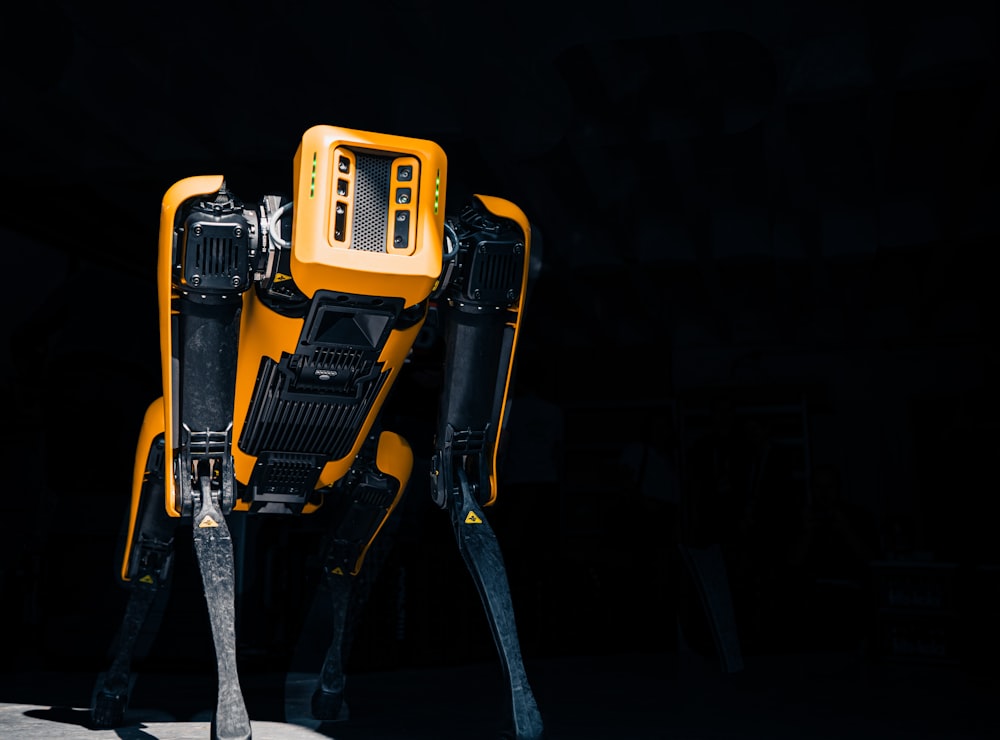 a yellow and black robot standing in the dark