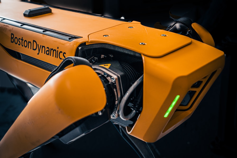 a close up of an orange robot with a green light