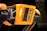 A detailed view of a robotic device featuring a bright orange casing with multiple cameras or sensors. The design includes perforated sections for ventilation and exposed mechanical parts, indicating advanced technology and engineering.