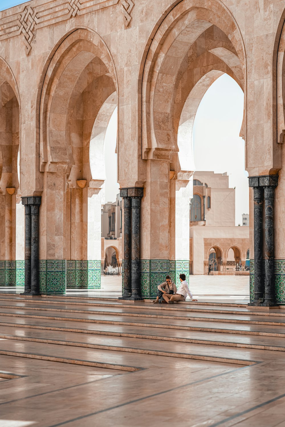 a couple of people sitting on the ground in front of a building