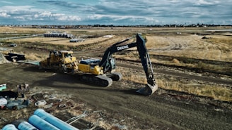 Heavy construction machinery working on a large-scale infrastructure site under a clear sky.