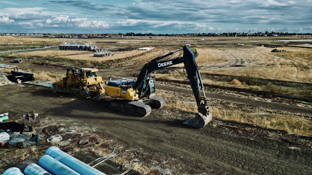 Heavy construction machinery working on a large-scale infrastructure site under a clear sky.