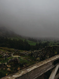 A misty morning over the lush green hills and ancient stone walls of the Irish countryside.