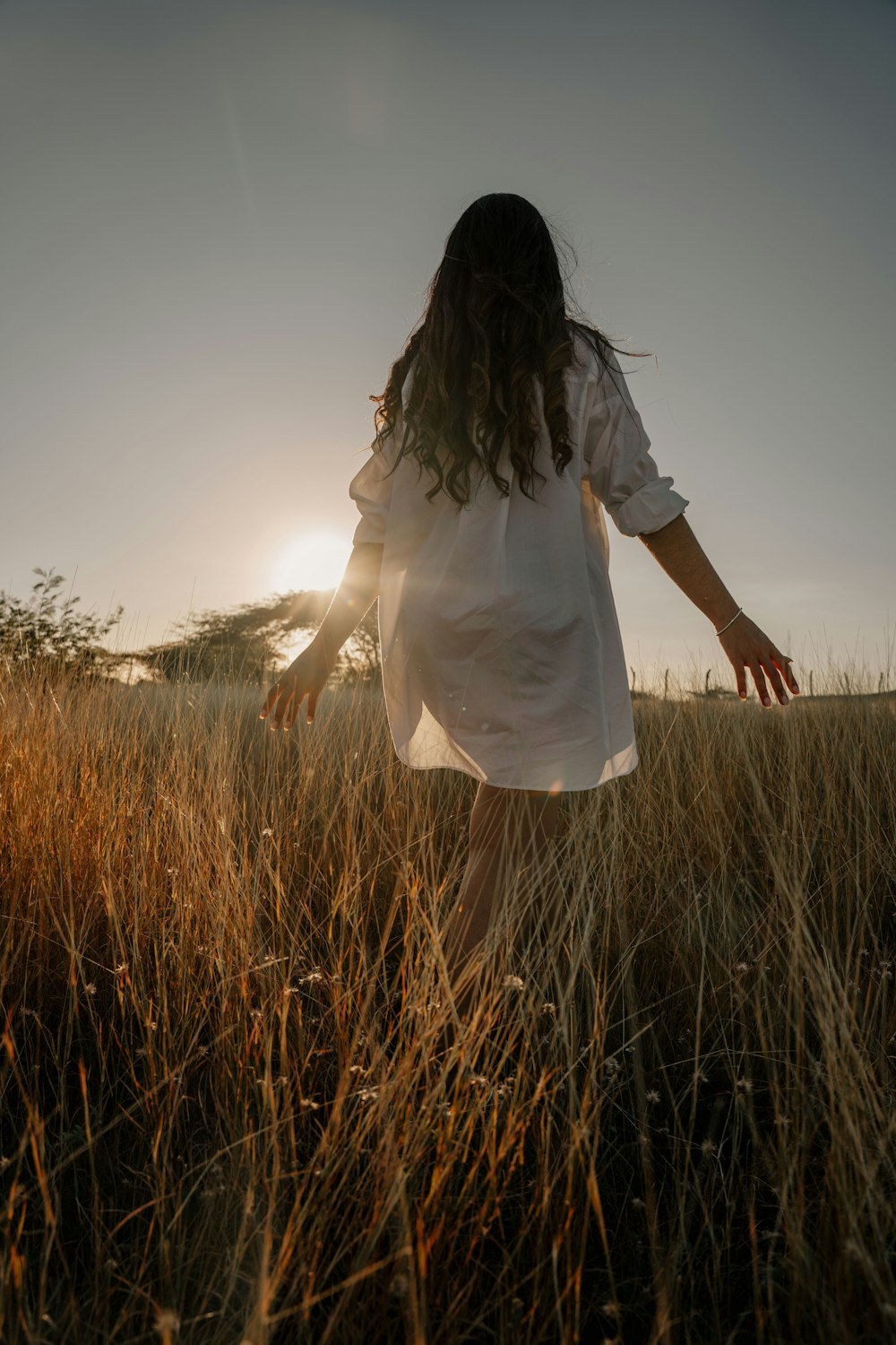 a woman walking through a field of tall grass