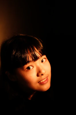 A young student illuminated by warm stage lights during a theatrical monologue.
