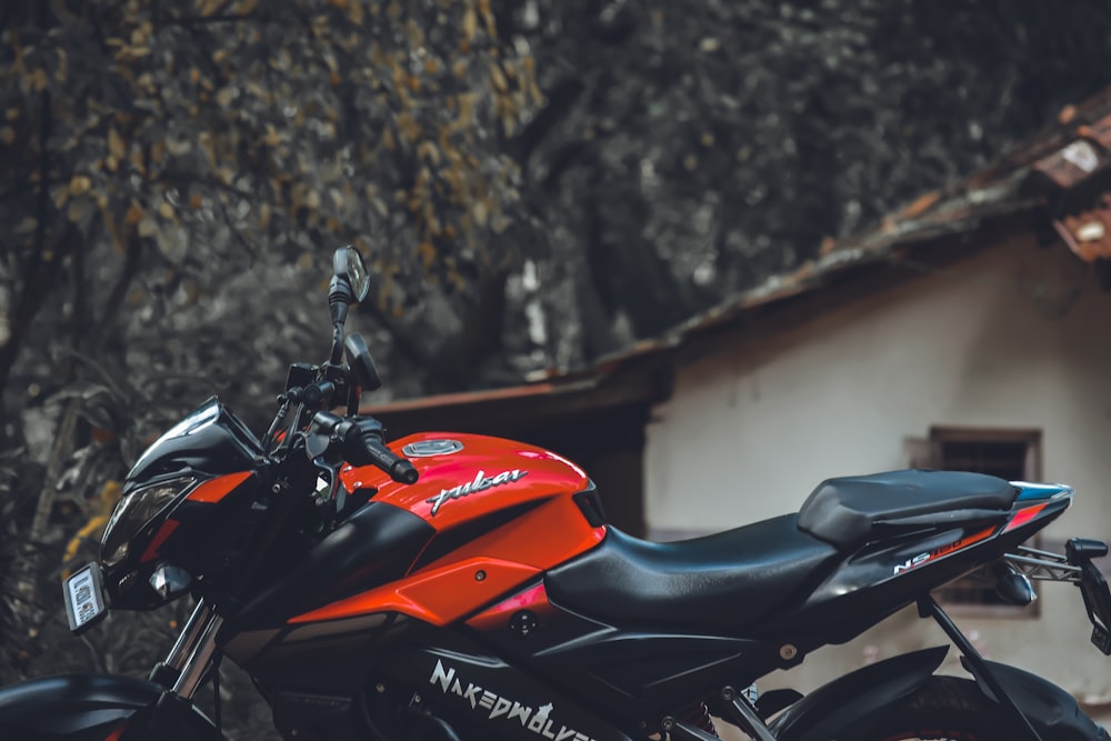 a red and black motorcycle parked in front of a building