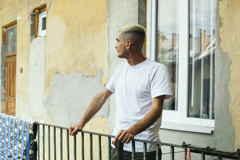 a man standing next to a fence near a building