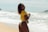 a woman in a yellow shirt standing on a beach