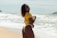 a woman in a yellow shirt standing on a beach