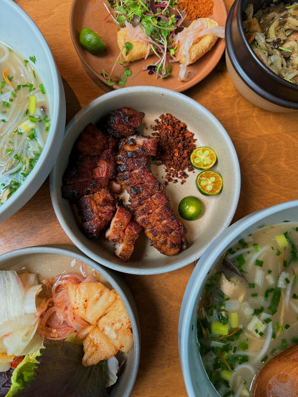 a wooden table topped with bowls of food