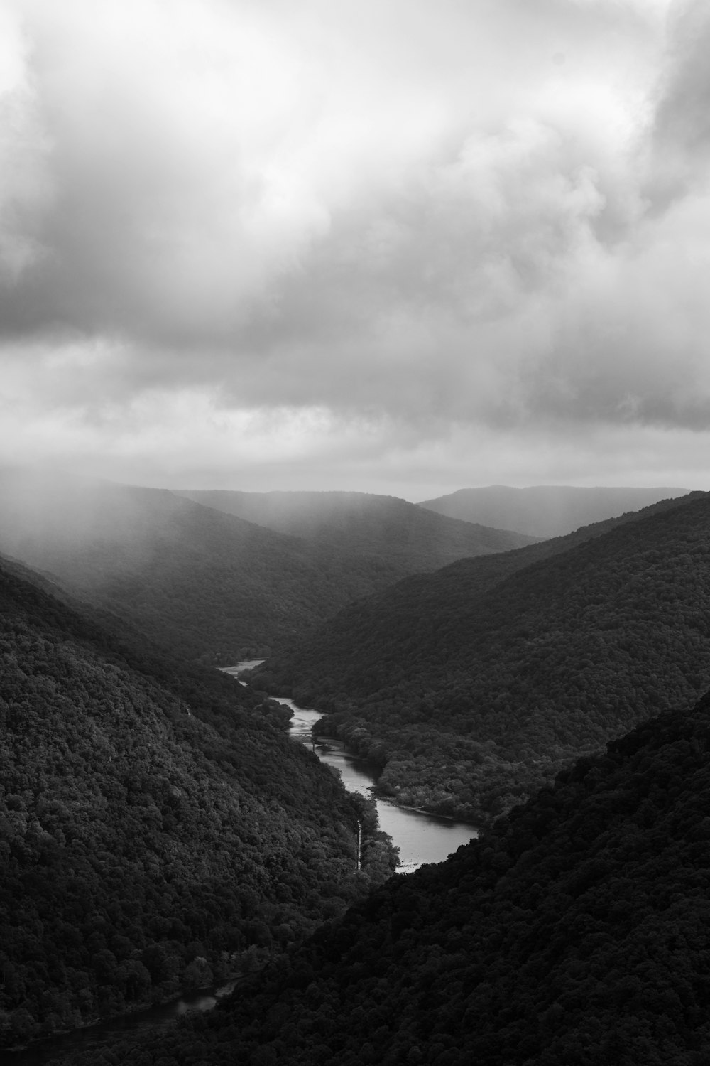 a black and white photo of a river in the mountains