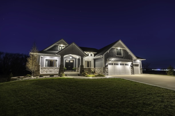 Elegant house with a modern façade, a driveway, and evening lighting highlighting its features.