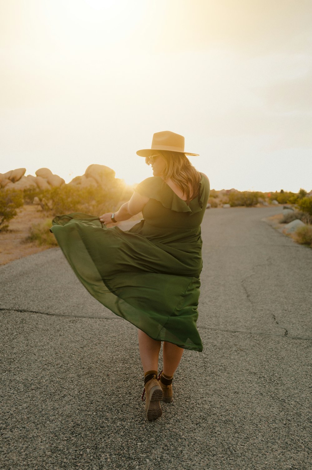 a woman in a dress and hat walking down a road