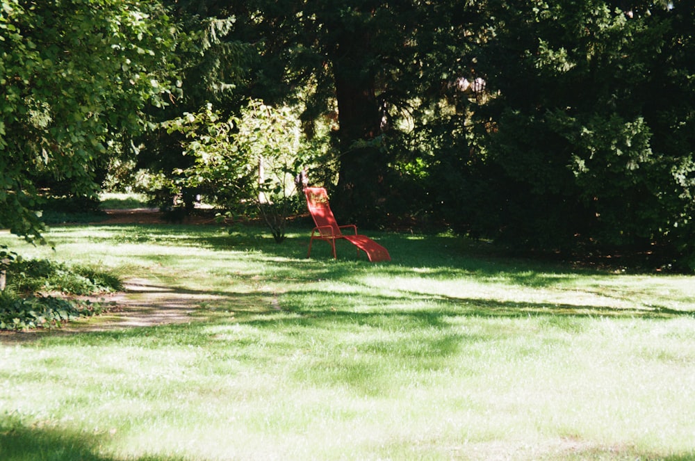 a red lawn chair sitting on top of a lush green field