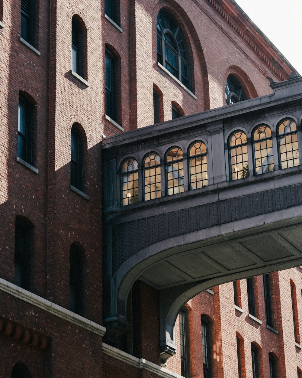 a large brick building with arched windows under a bridge