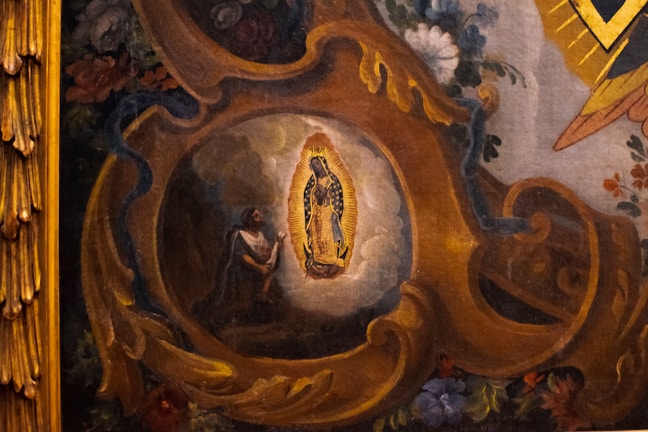 A detailed painting depicts a religious scene with a central figure illuminated by an intricate golden frame. Surrounding the figure are rich floral decorations and swirling ornate patterns in warm tones. The artwork conveys a sense of devotion and reverence.