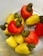 A collection of ripe and colorful cashew fruits, with a combination of yellow and red cashew apples, each topped with a green cashew nut. The fruits are placed together in a light-colored container, creating a vibrant contrast.