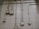 An interior wall is covered with a grid of beige tiles. Several electrical conduits run vertically and horizontally across the surface, connecting multiple junction boxes affixed to the wall. One of the boxes is marked with the letter 'N'. The overall appearance is industrial and functional.
