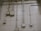 An interior wall is covered with a grid of beige tiles. Several electrical conduits run vertically and horizontally across the surface, connecting multiple junction boxes affixed to the wall. One of the boxes is marked with the letter 'N'. The overall appearance is industrial and functional.