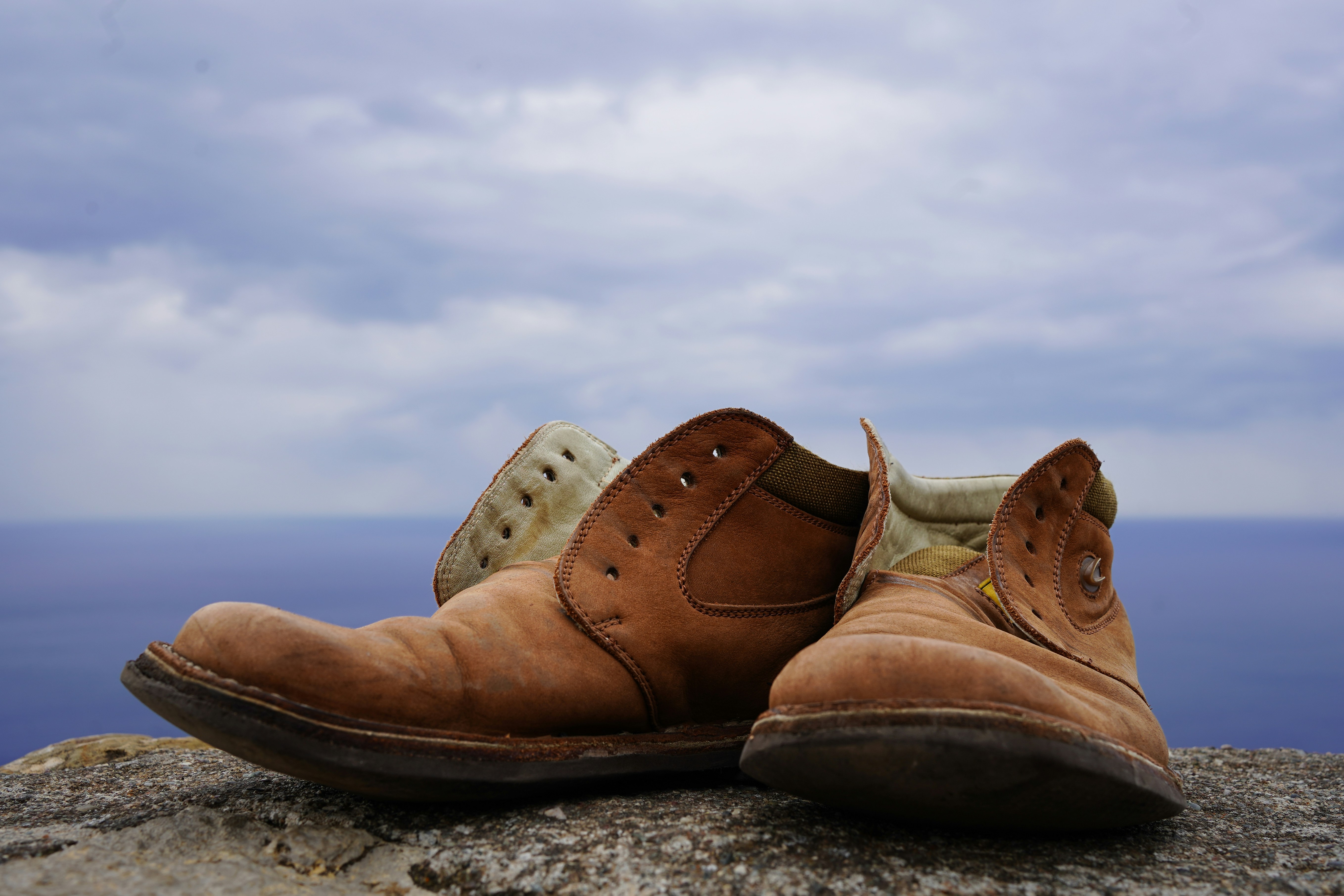 a pair of brown shoes sitting on top of a rock