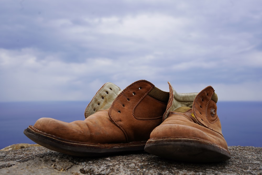a pair of brown shoes sitting on top of a rock
