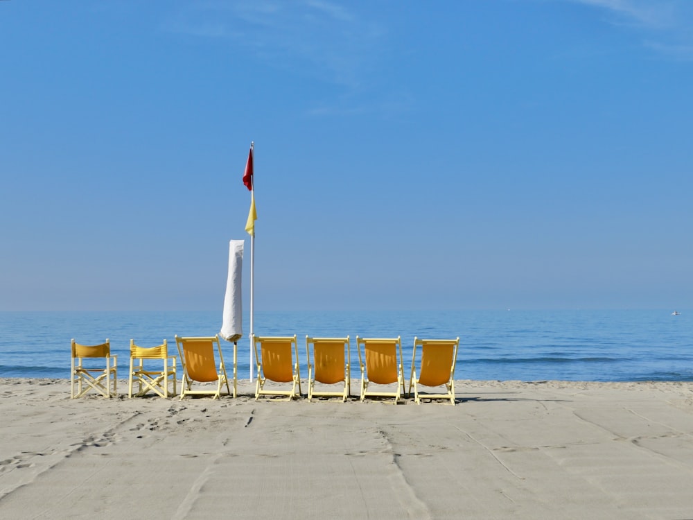 a row of chairs sitting on top of a sandy beach