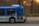A public transit bus from the Edmonton Transit Service is captured in motion. The side of the bus shows advertisements and an electronic display indicates the destination as Capilano with route number 4. Inside, passengers are visible through the windows as they travel.