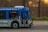 A public transit bus from the Edmonton Transit Service is captured in motion. The side of the bus shows advertisements and an electronic display indicates the destination as Capilano with route number 4. Inside, passengers are visible through the windows as they travel.