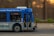 A public transit bus from the Edmonton Transit Service is captured in motion. The side of the bus shows advertisements and an electronic display indicates the destination as Capilano with route number 4. Inside, passengers are visible through the windows as they travel.