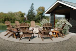 Outdoor teak lounge chairs arranged around a fire pit on a wooden deck.