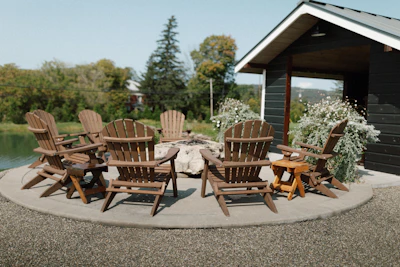 Outdoor teak lounge chairs arranged around a fire pit on a wooden deck.