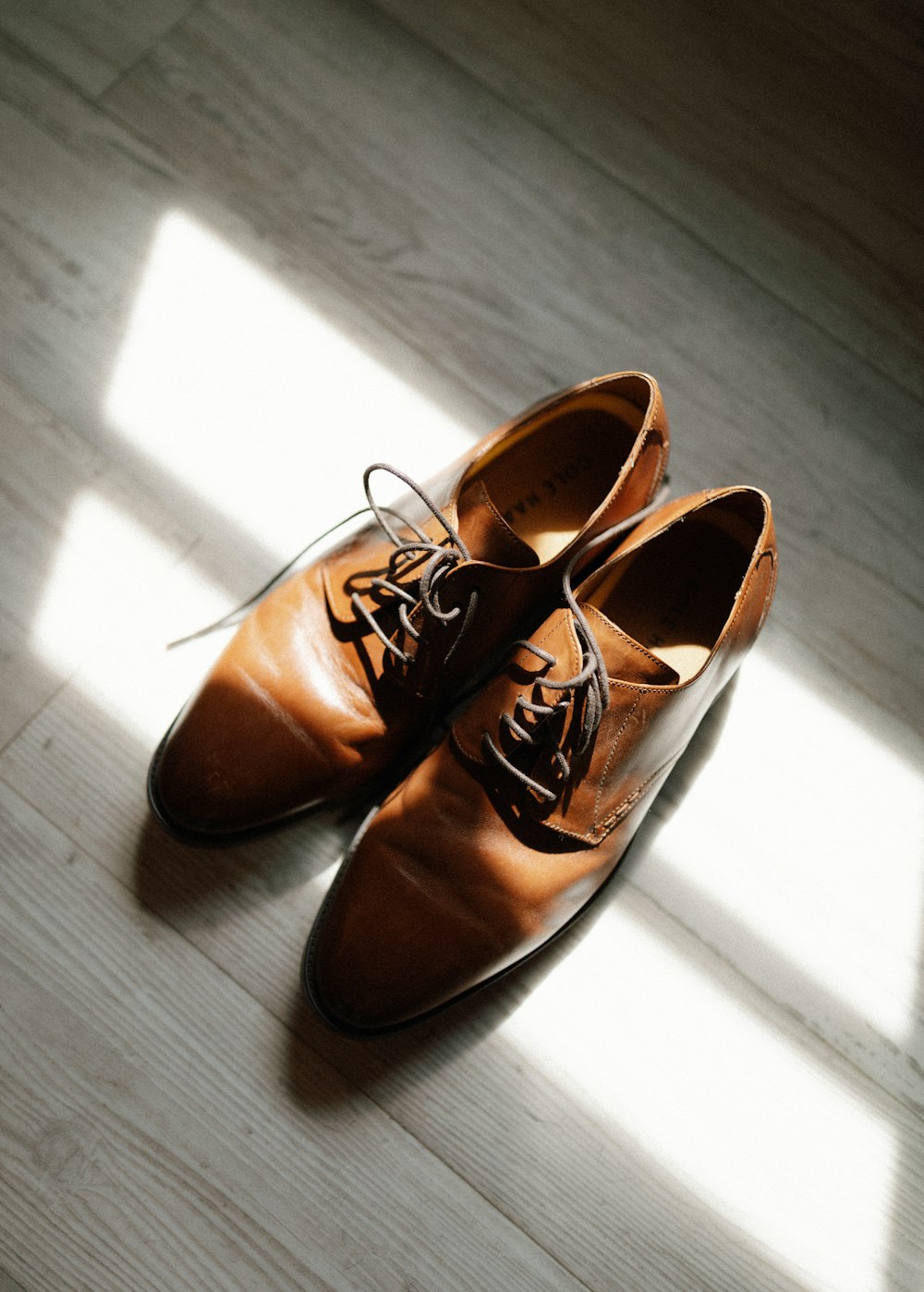 a pair of brown shoes sitting on top of a wooden floor