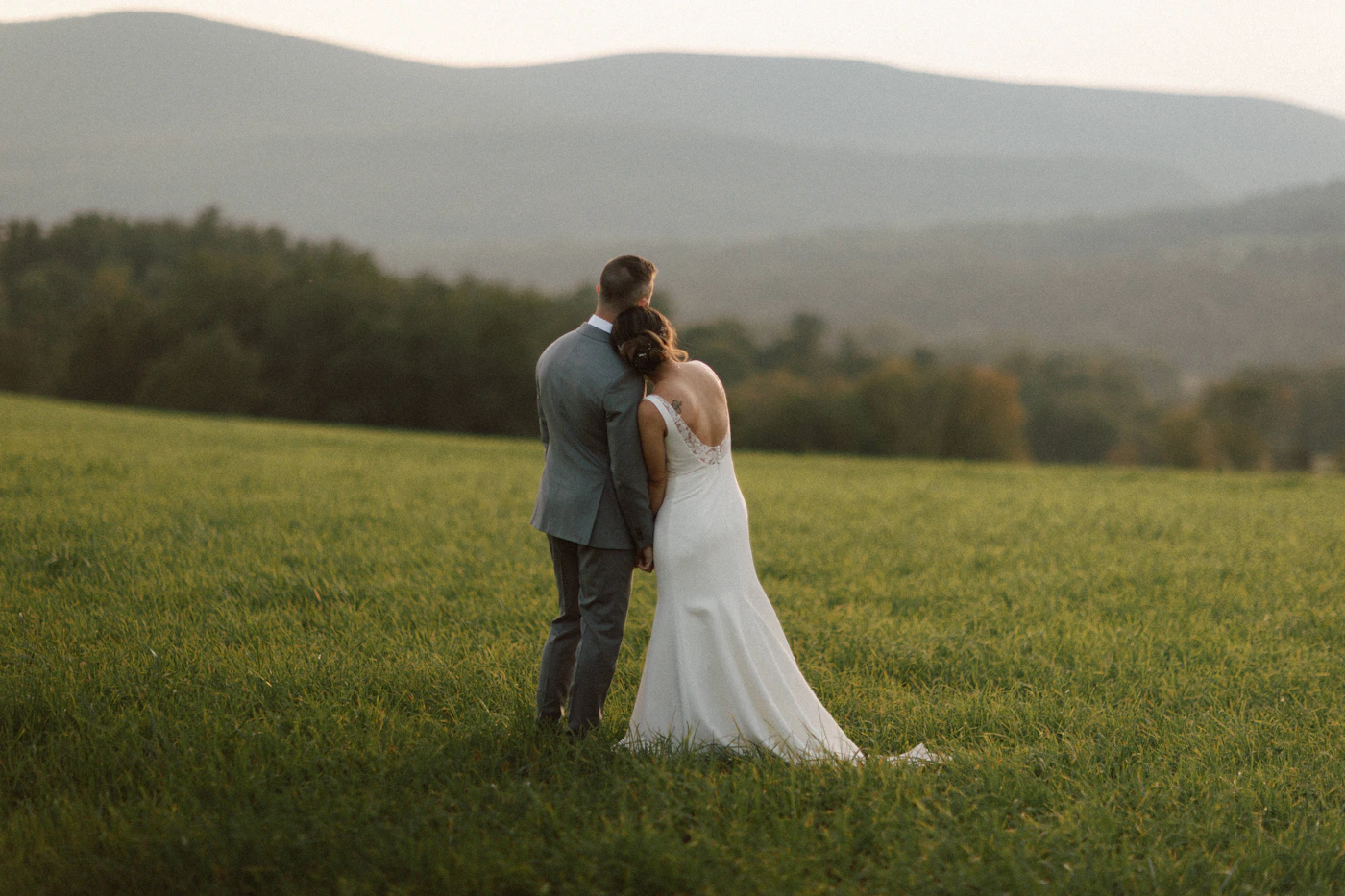 A bride and groom standing together outdoors in their wedding attire for a portrait at their destination wedding with natural light and the open landscape visible around them