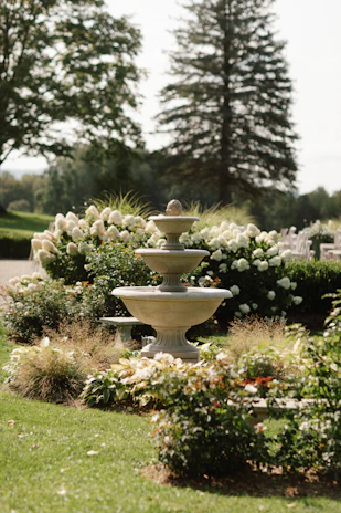A peaceful garden courtyard with blooming flowers and a water fountain.