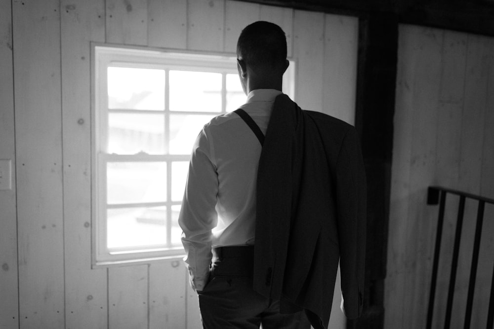 a man in a suit and tie looking out a window