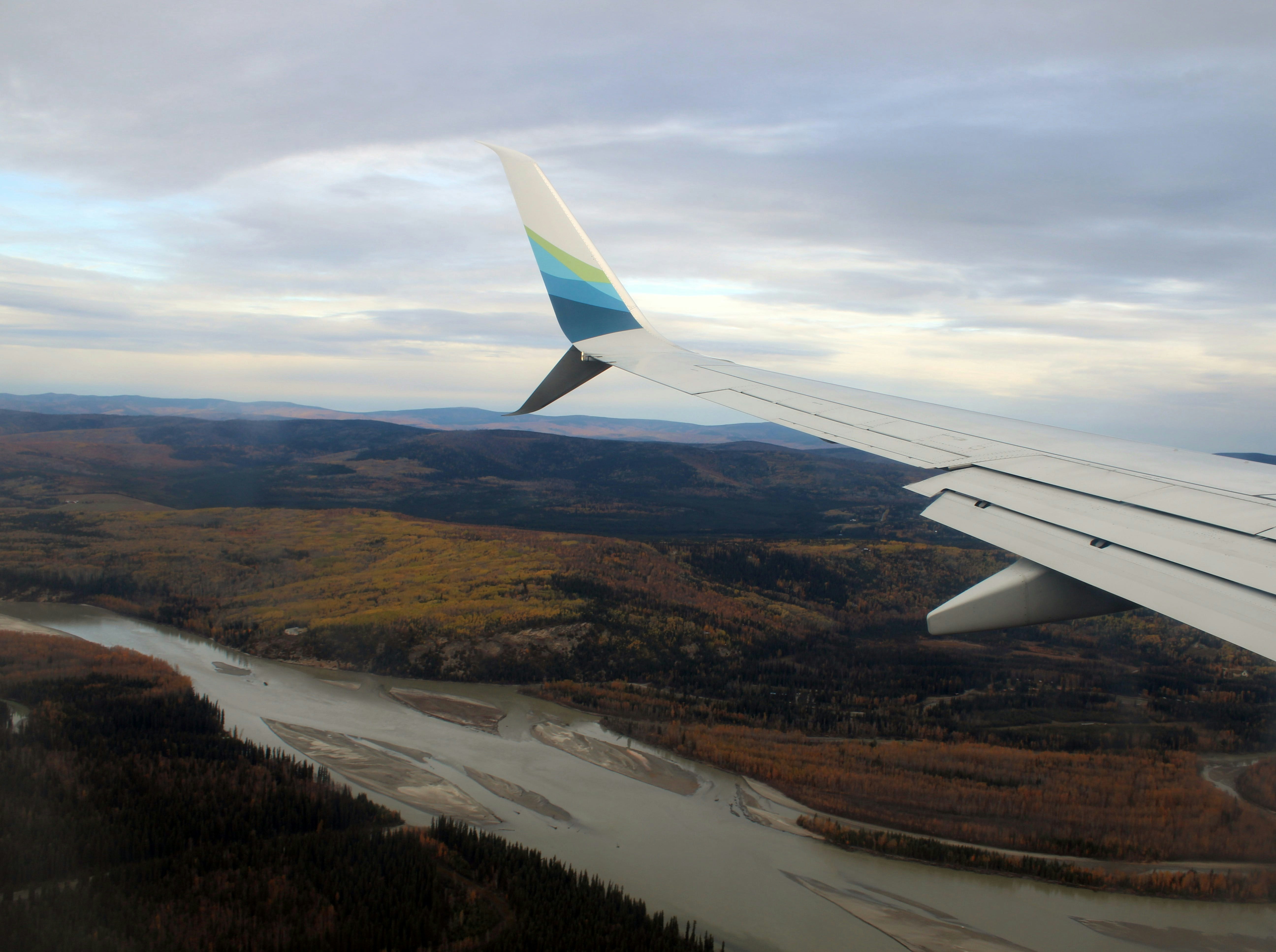 the wing of an airplane flying over a river, 