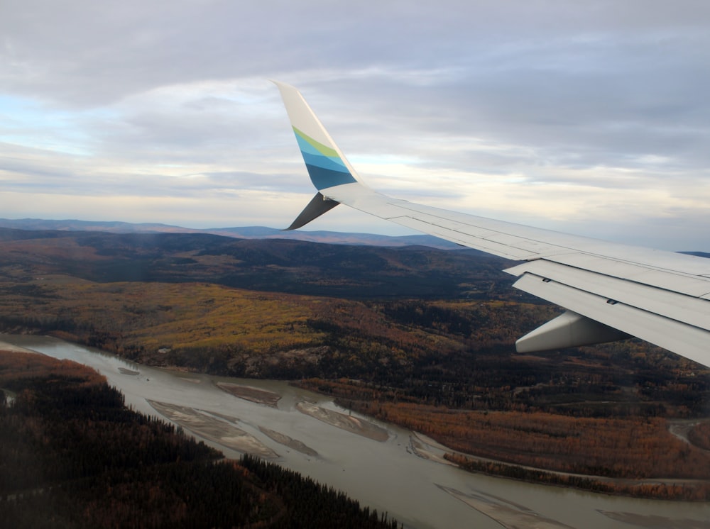 the wing of an airplane flying over a river