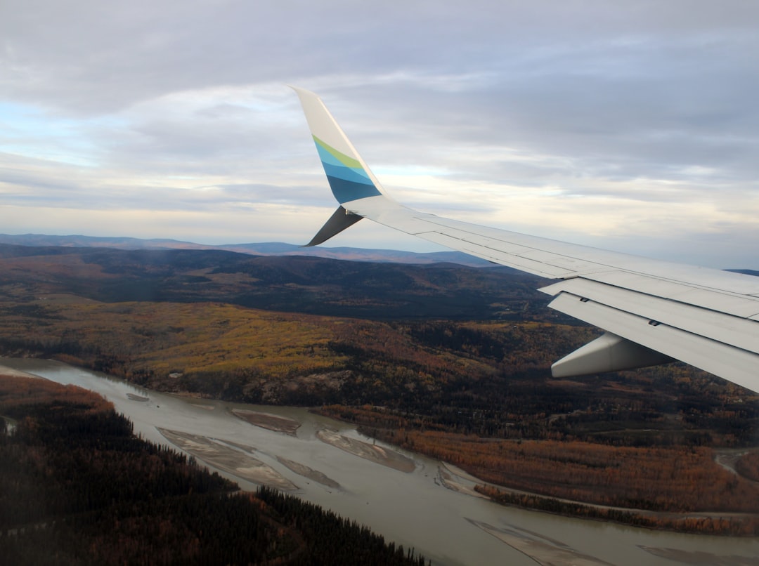 the wing of an airplane flying over a river,