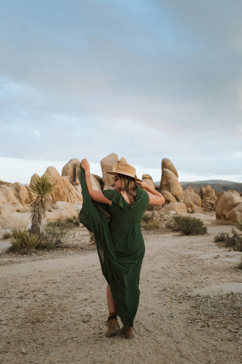 a woman in a green dress and hat in the desert