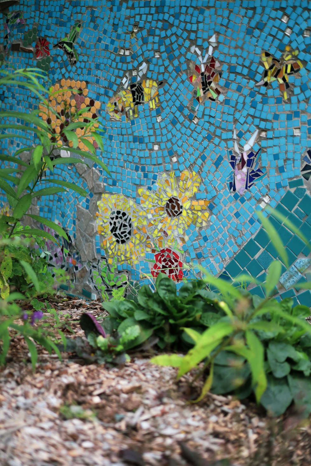 a mosaic wall with flowers and butterflies on it