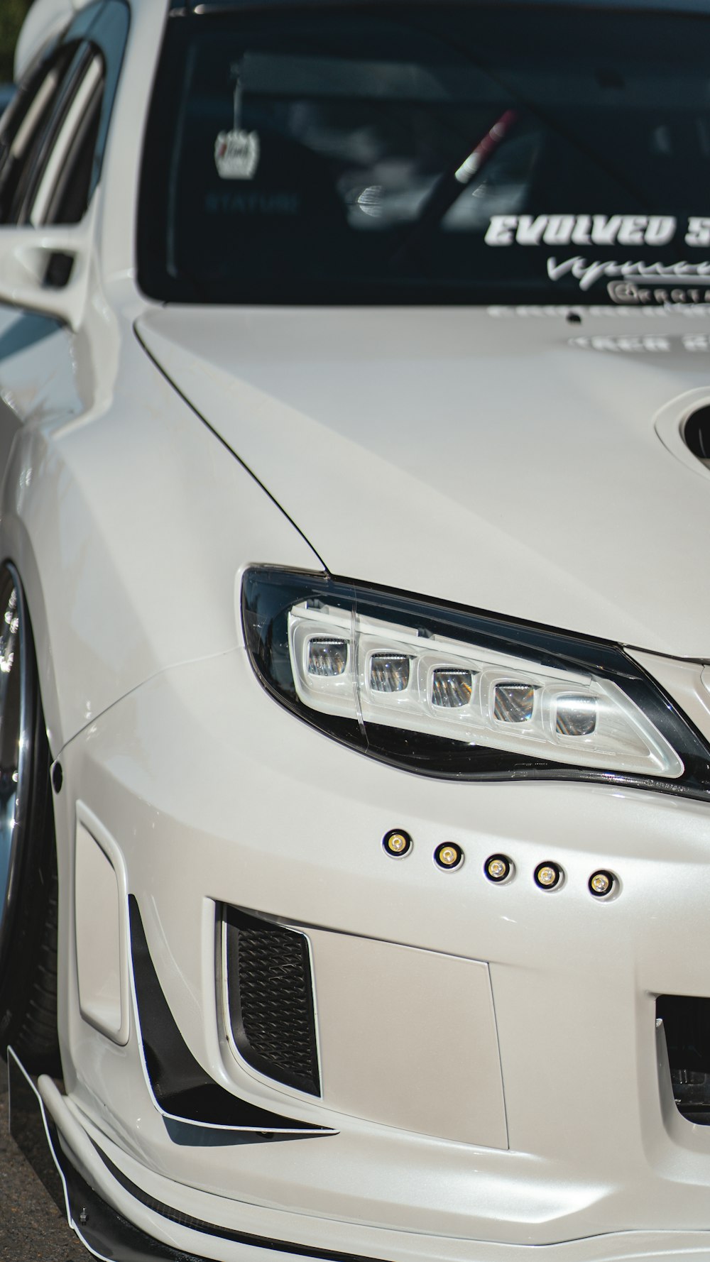 the front of a white car parked on the side of the road