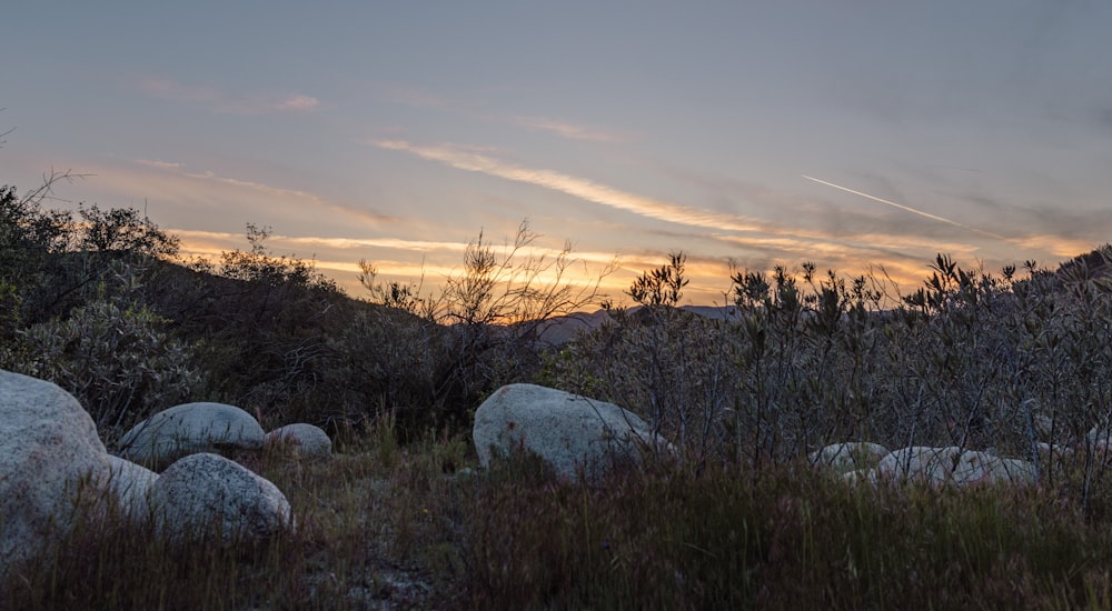 the sun is setting over the mountains and rocks