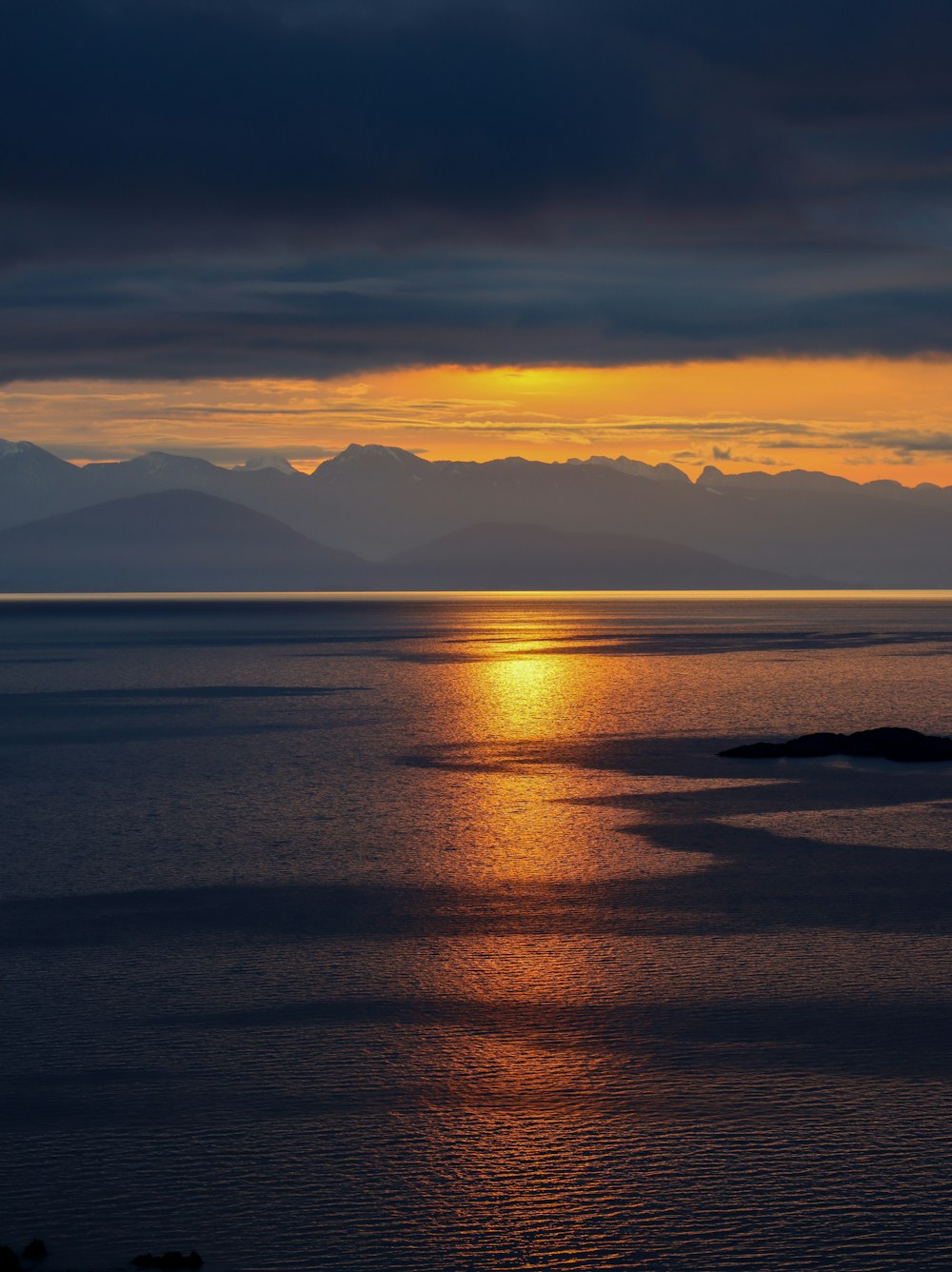 a large body of water with a sunset in the background