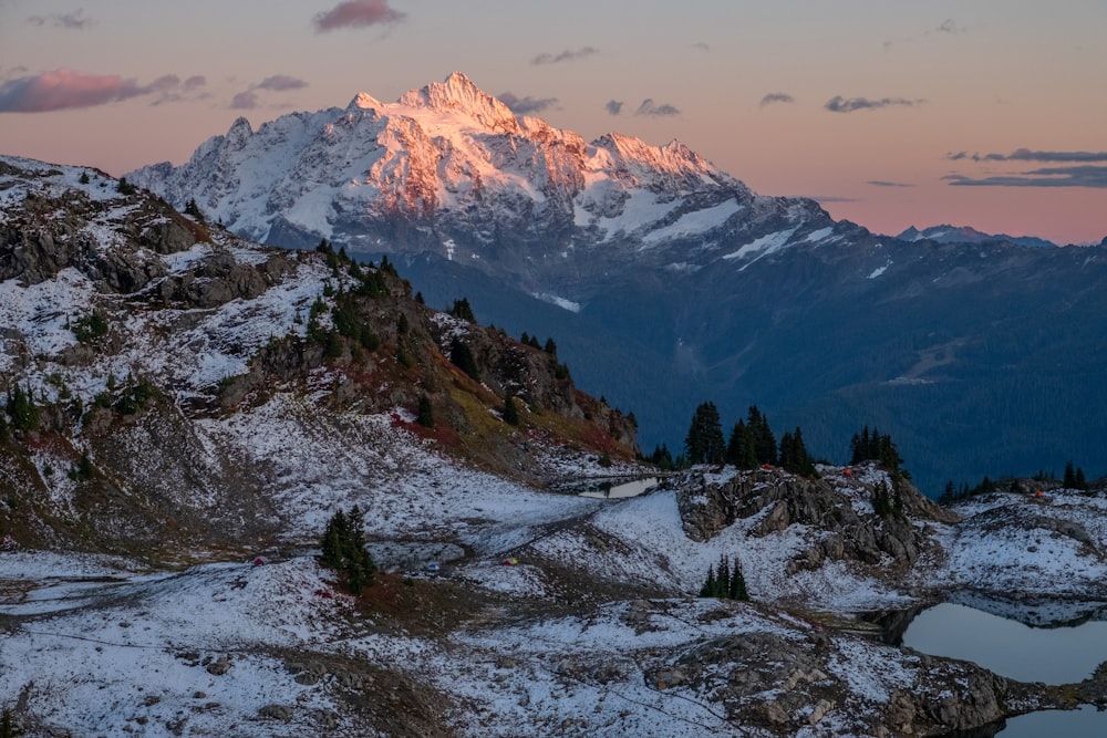 a snow covered mountain with a lake in the foreground